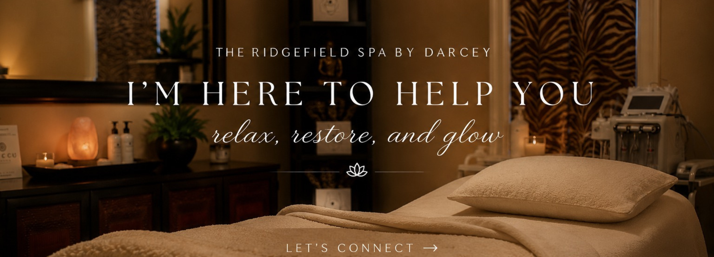 Luxury spa treatment room at The Ridgefield Spa by Darcey in Ridgefield, CT with a beautifully prepared massage table, soft beige linens, warm candlelight, and a relaxing atmosphere.
